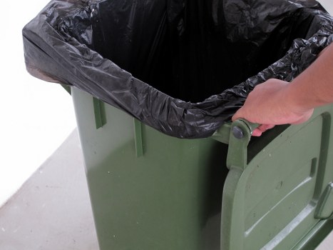 Pile of garden waste being loaded into a skip on a suburban driveway